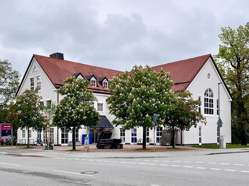Ansicht der Gemeindebibliothek Grünwald, blühende Kastanien im Vordergrund des Bildes.