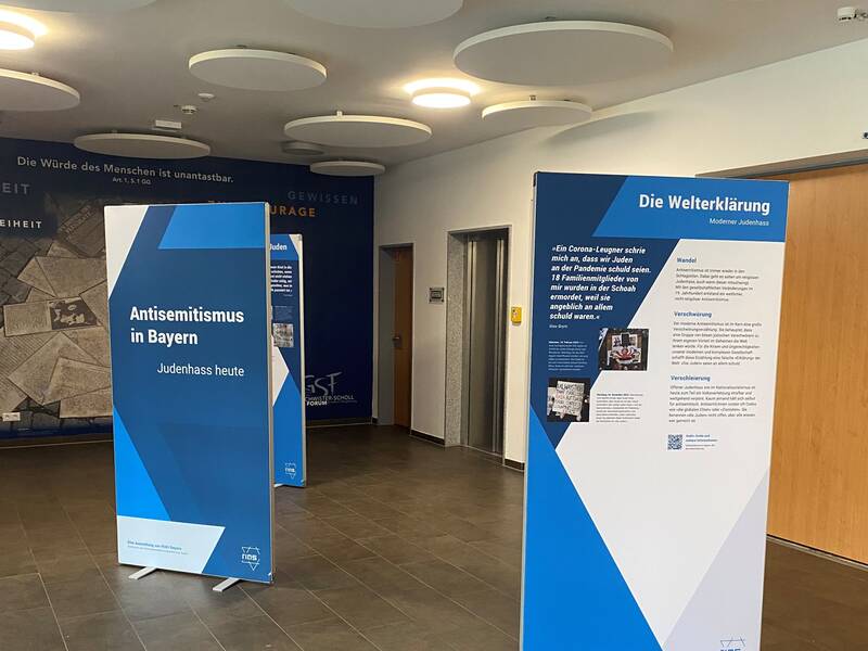 In einem Foyer stehen Leinwände mit Informationen über Antisemitismus in Bayern. 