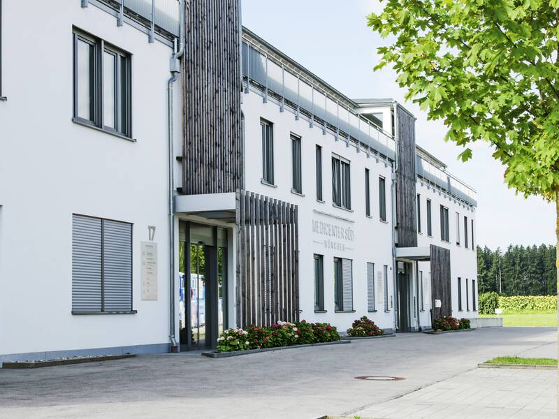 Auf einem großen weißen Gebäude steht in grauen Buchstaben: Medicenter München Süd.
