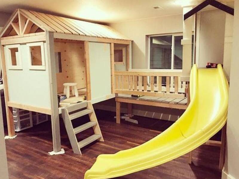In einem Kinderzimmer schwingt sich eine gelbe Rutsch aus einem Spielhaus.