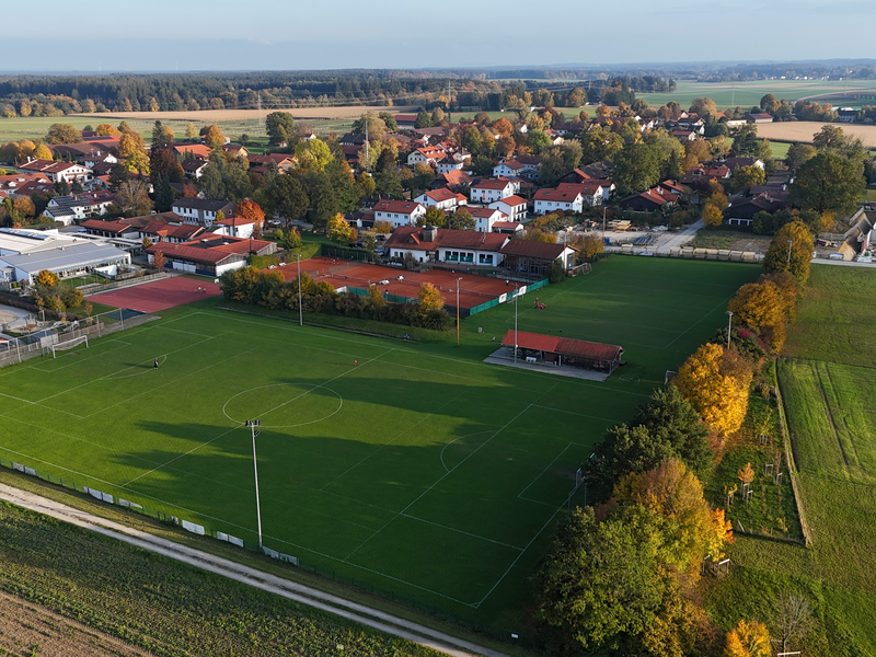 Ein Fußballplatz in einem Dorf von kleinen Häusern umgeben in herbstlicher Stimmung.