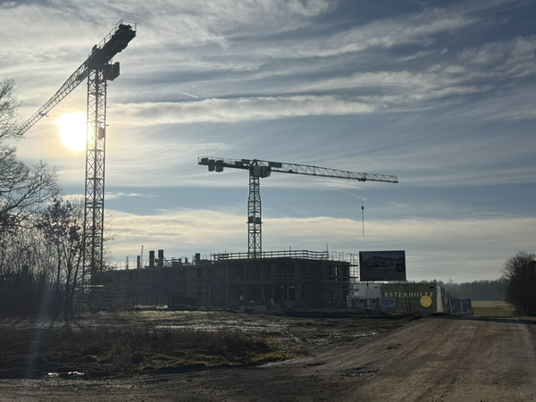 Eine Baustelle mit zwei großen Baukränen im Sonnenuntergang.
