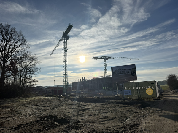 Eine Baustelle mit Bauzaun und Bautafeln mit der Aufschrift Esterholtz. 