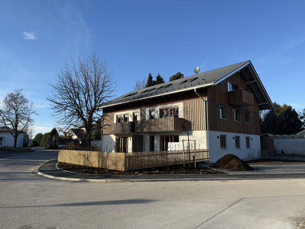 An einer Weggabelung steht ein großes, teils mit Holz verkleidetes, Haus.