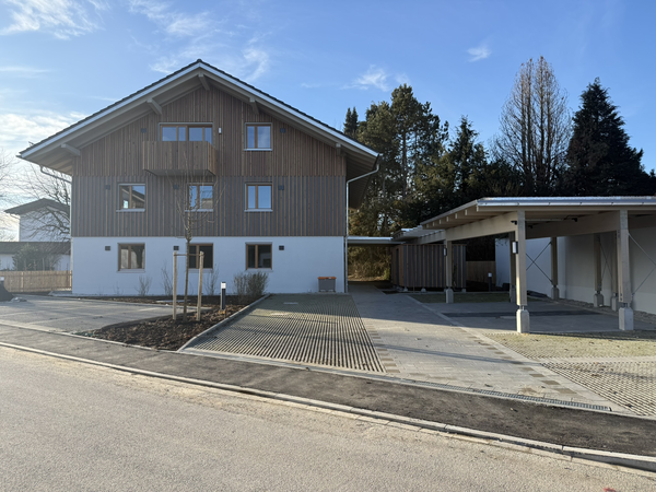 Ein frisch gepflasterter Weg führt zu einem dreistöckigen Gebäude mit Balkonen.