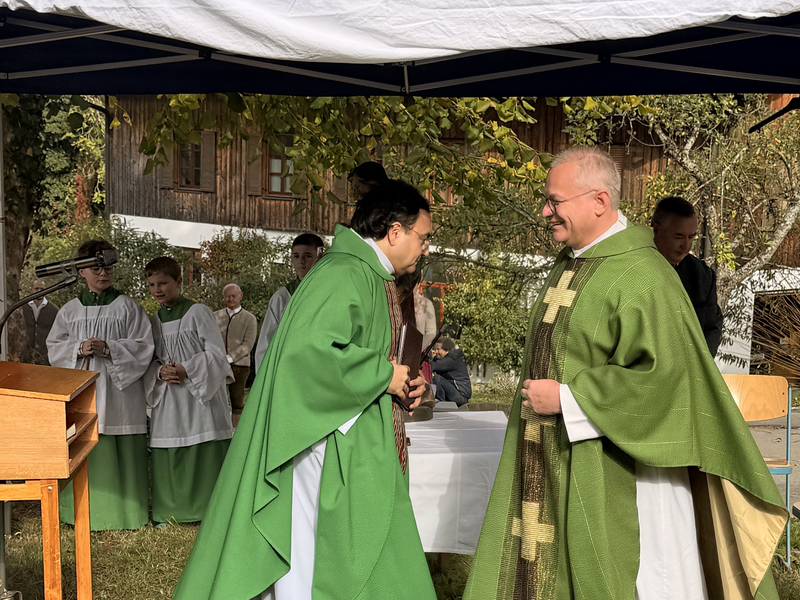 Weihung der Kapelle Beigarten. Zwei Pfarrer stehe sich gegenüber am improvisierten Altar im Freien.